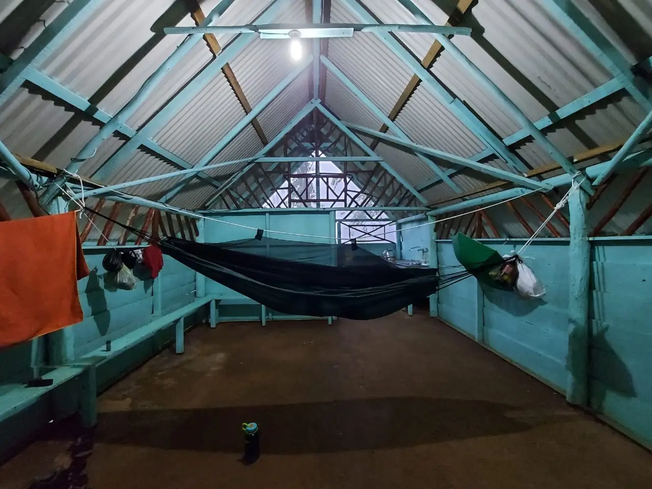 Open houten hut met een hangmat onder een dak van schuine balken