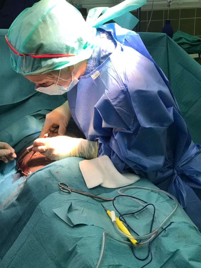 Chirurg in blauwe operatiekleding tijdens een operatie