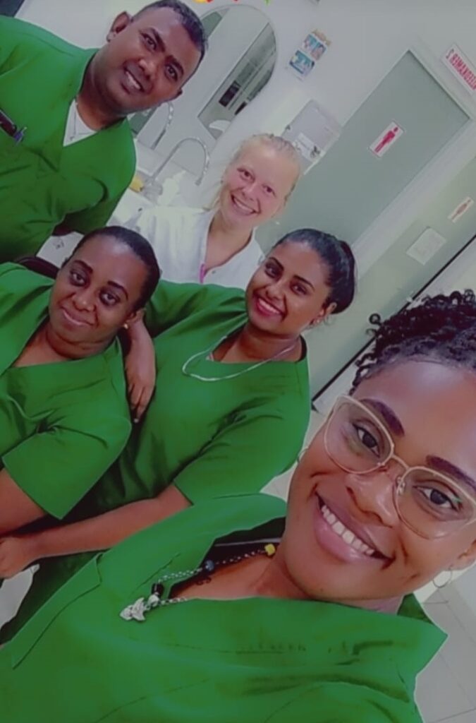 Vier lachende collega’s in groene kleding maken een selfie