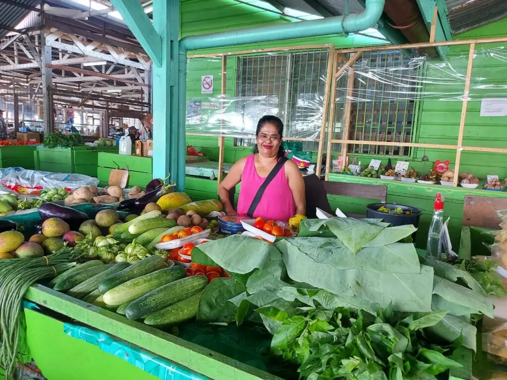 Marktkraam met groenten en een lachende verkoopster