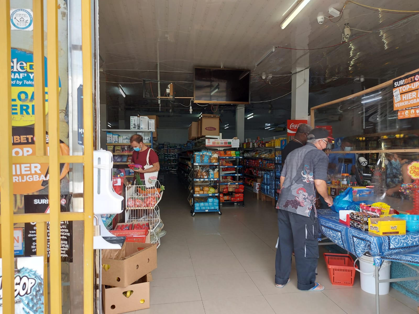 Binnenkant van een winkel vol met spullen, een klant staat bij de toonbank