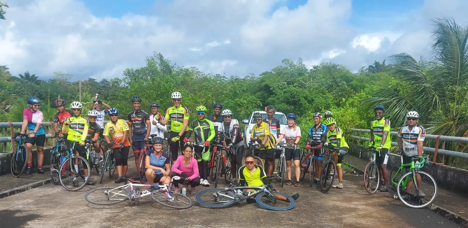 Groep wielrenners poseert met hun fietsen bij een brug