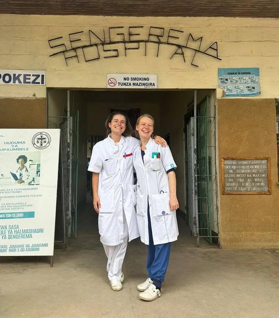 Twee mensen in witte jassen staan voor de ingang van het Sengerema Hospital