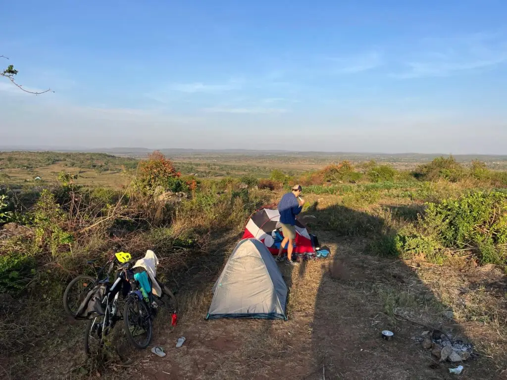 Tentje en twee fietsen op een heuvel met uitzicht over het landschap
