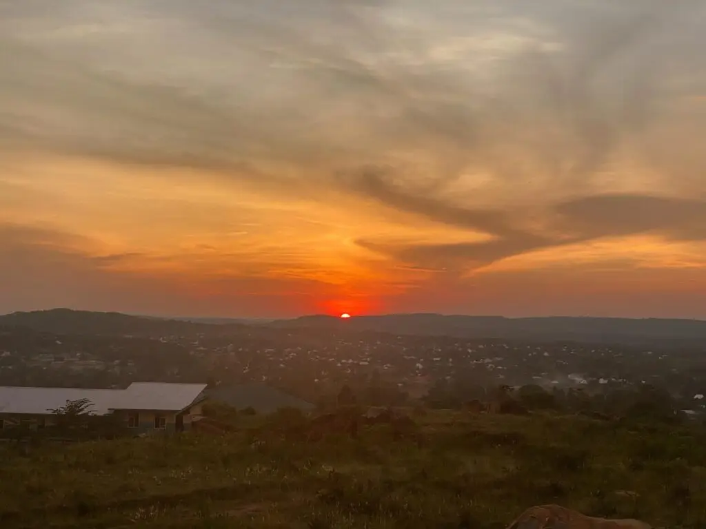 Rode zon zakt achter een heuvellandschap onder een oranje wolkenlucht