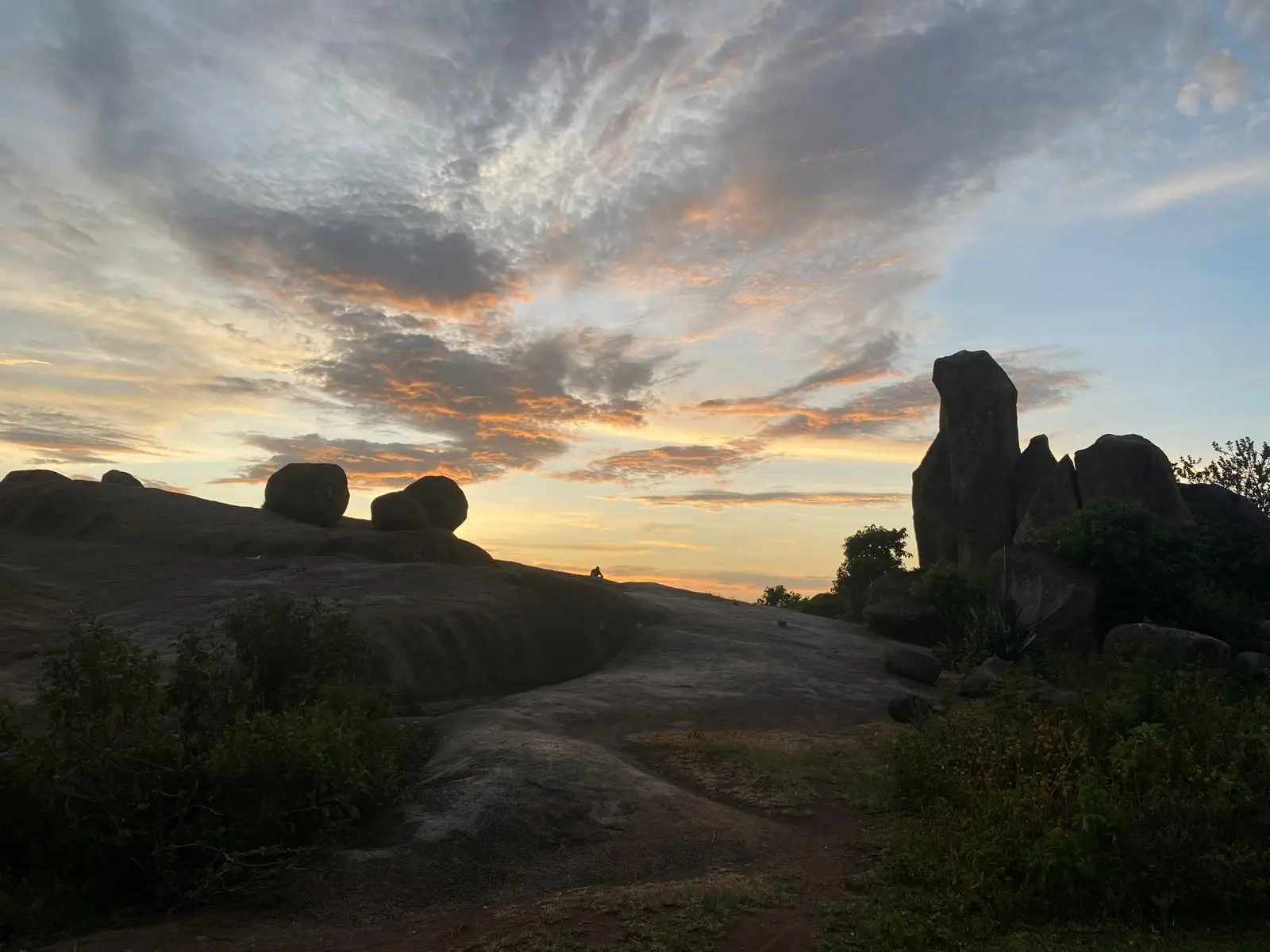 Zonsondergang boven grote rotsblokken en een heuvelachtig landschap