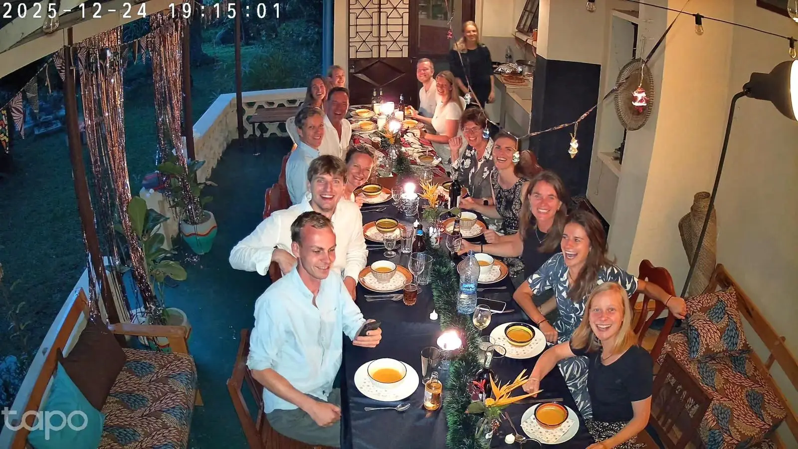 Grote groep mensen eet samen aan een lange tafel met sfeerverlichting