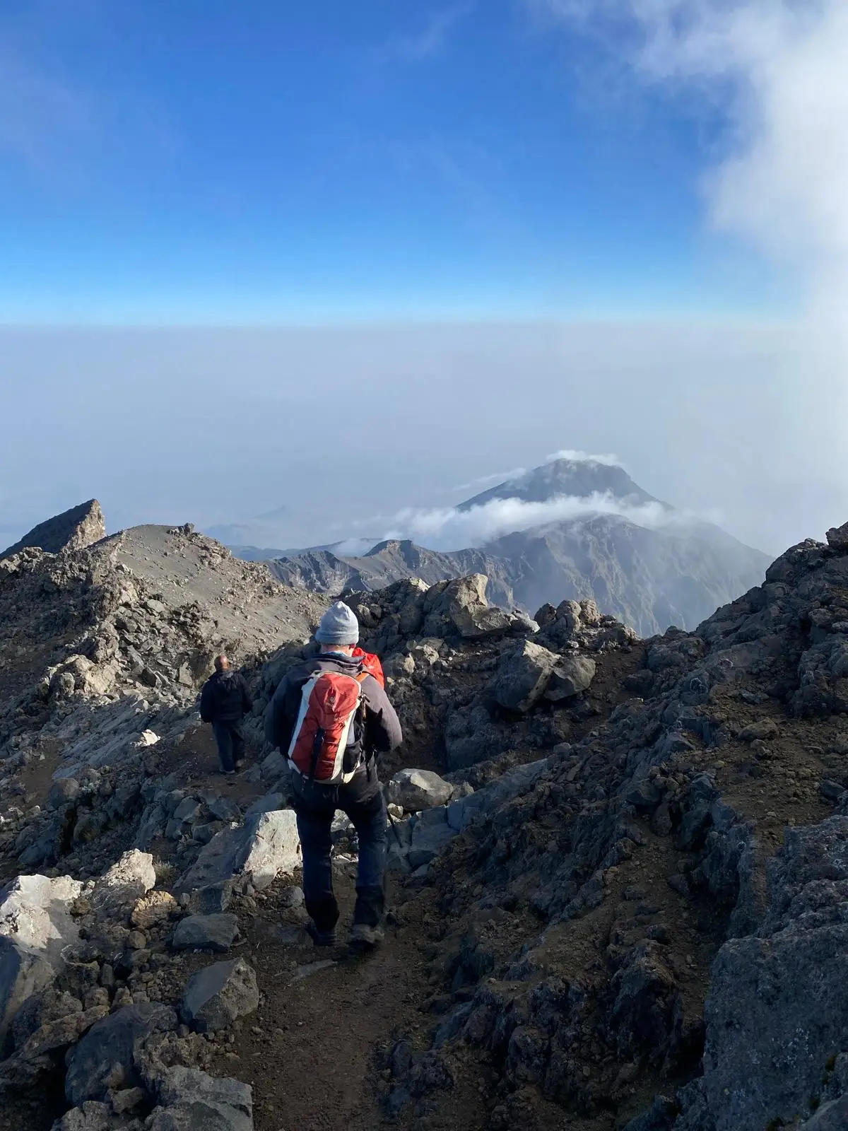Wandelaar met rugzak op een rotsig pad in de bergen, met een bergtop in de mist