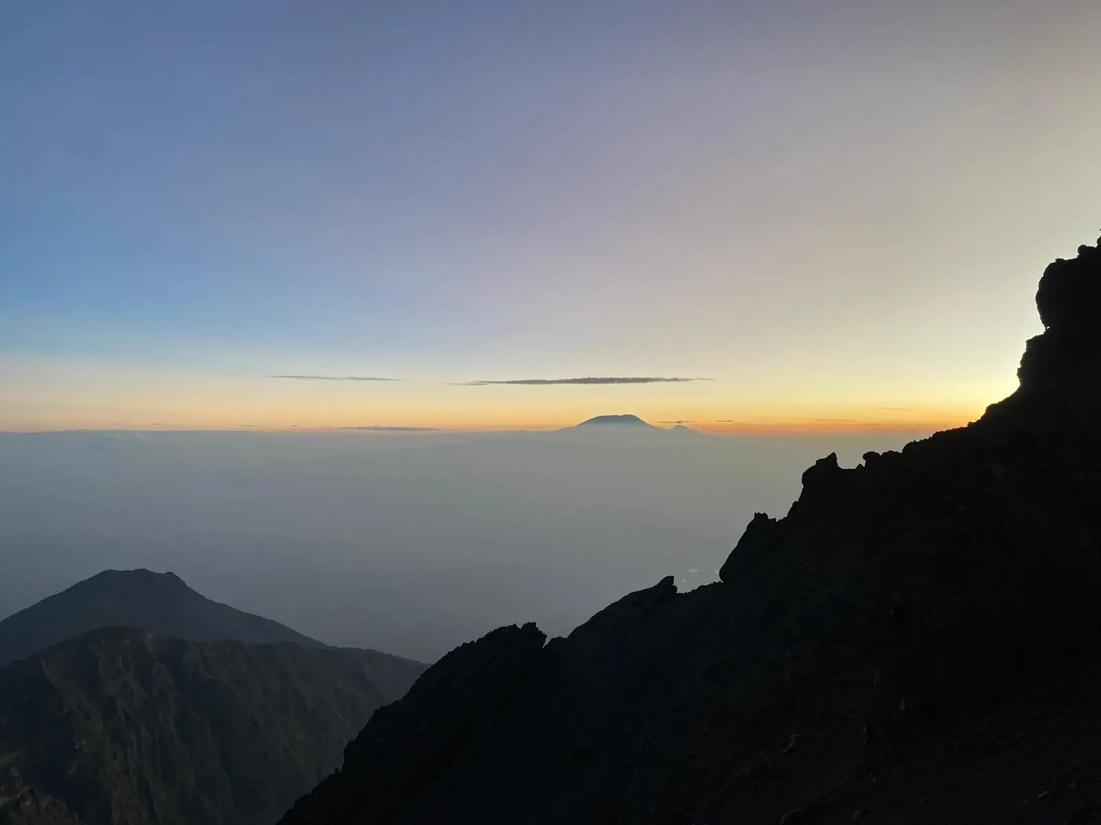 Zonsopgang boven de wolken met een oranje lijn aan de horizon