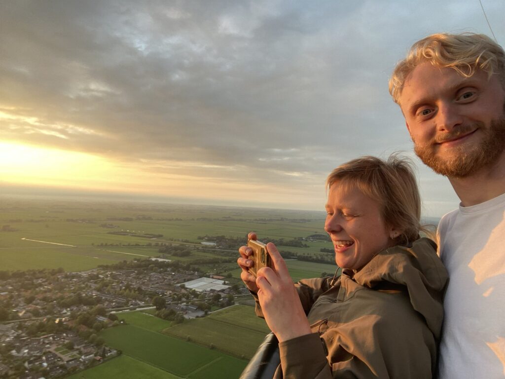 Lotte en Floris tijdens een ballonvaart boven groene weilanden